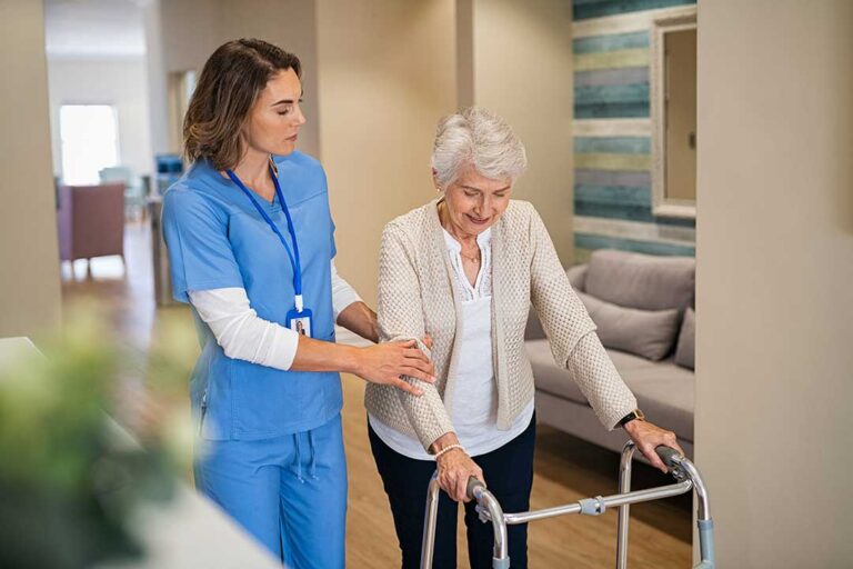 Adult daughter sitting with elderly mother, reviewing documents together at a table in a comfortable shared living space.