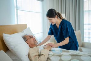 Older couple sharing a meal in a bright assisted living apartment while a caregiver offers discreet support