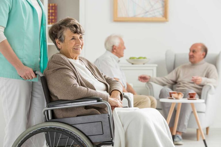 Older adult and family member arrange photographs and clothing in a bright assisted living room.