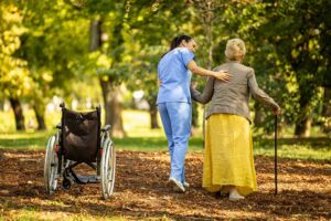 Older adult arranging family photos and a favorite chair in a bright assisted living apartment.